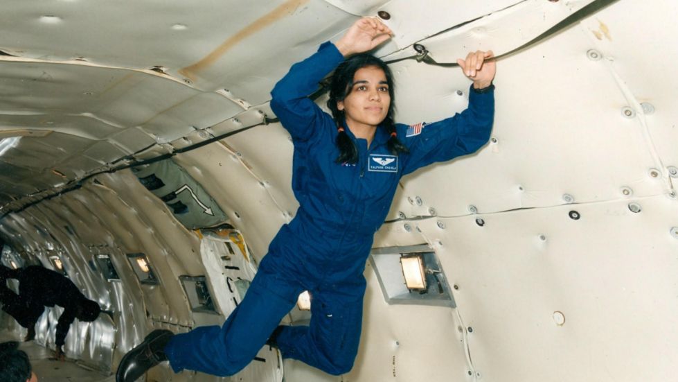Kalpana Chawla in a blue space suit floating in a space shuttle.